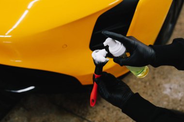 İşçi hava emme sistemini köpük ve deterjanla fırçayla temizliyor. Profesyonel araba yıkama oturumunda fırçalamak için deterjan uygulaması