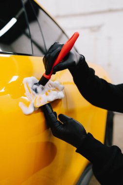 Araba tutacağı mikrofiber ve deterjan ile oto yıkama servisinde. Temizlikçi, araba yıkadıktan sonra araba sapını fırçalıyor.