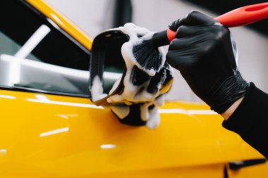 Araba aynasına sabun solüsyonu sürme prosedürü. Araba yıkama yerindeki toz ve kiri temizlemek için çok titiz bir araç.