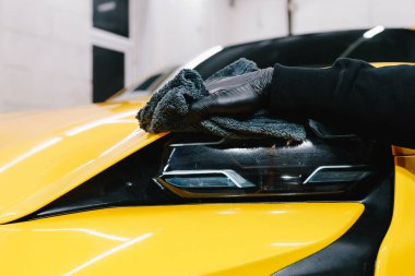 Spor araba temizleme işlemi. Farı mikrofiber bezle parlatmak. İşçi araba farı cilası için mum sıvısı kullanır