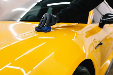 Detaylı servis çalışanı spor arabaya seramik koruma sıvısı uygular. Sarı spor araba için koruyucu nano katman oluşturmak için seramik sıvıyı karıştırmak