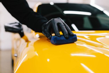 Detaylı servis çalışanı spor arabaya seramik koruma sıvısı uygular. Sarı spor araba için koruyucu nano katman oluşturmak için seramik sıvıyı karıştırmak