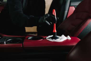 Araba yıkatma işlemi araba yıkamada sabun köpüğüyle temizleniyor. Adam arabanın kırmızı derisine köpük sürüp temizler.