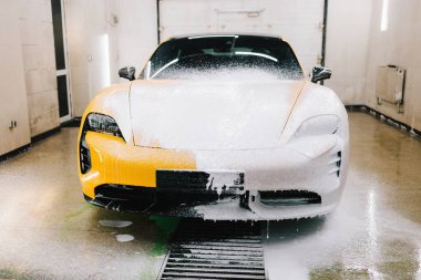 İşçi sabun solüsyonunu oto yıkama için yüksek basınçlı su jeti ile spreyliyor. Spor araba temizliği için yüksek basınçlı su tabancası olan sabunlu köpük uygulaması.