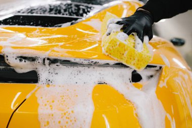 Araba servisinde temizlik için köpüklü süngerle araba yıkamak. Detaylandırmak için ayarlanmış bir araba hazırlanıyor
