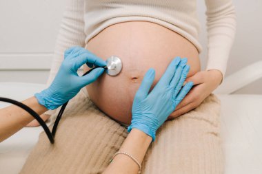 Hamilelik kontrolü. Jinekolog ve steteskoplu bir jinekolog jinekoloji kliniğindeki randevuda bebeğin kalp atışlarını dinliyor.