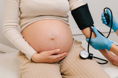 Hamilelik sırasında yüksek basınç sorunu. Jinekolog, doğum merkezinde hamile bir hasta için kan basıncını ölçer.