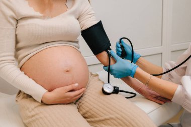 Hamilelik sırasında yüksek basınç sorunu. Jinekolog, doğum merkezinde hamile bir hasta için kan basıncını ölçer.