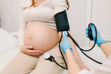 Hamilelik sırasında yüksek basınç sorunu. Jinekolog, doğum merkezinde hamile bir hasta için kan basıncını ölçer.