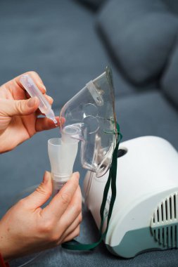 Solunum tedavisi için tıbbi çözelti damlatıyor. Evde kullanılmadan önce kompresör nebulizer hazırlama süreci