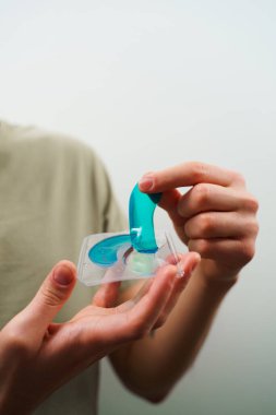 Cilt bakımı için yaşlanmayı önleyici nemlendirici göz maskesi. Erkek elleri mavi bir kolajen pedi tutuyor.