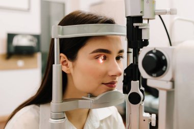 Kız göz muayenesi için göz doktorunu ziyaret ediyor. Göz ve kornea kontrolü için kesik lamba ile oftalmoloji prosedürü