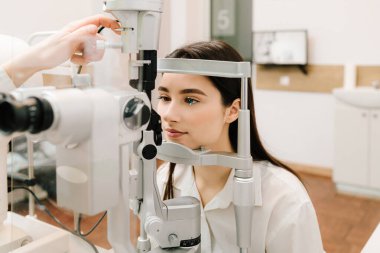 Kız göz muayenesi için göz doktorunu ziyaret ediyor. Göz ve kornea kontrolü için kesik lamba ile oftalmoloji prosedürü