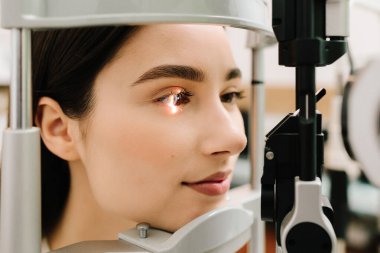 Göz farı ve kornea teşhisi, göz hekimliği kliniğinde. Kesik lambanın gözündeki ışık incelenmek için gözleri ve kızın korneası için.