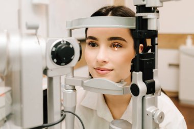 Oftalmolog, göz ve kornea teşhisi koymak için kesik lambadan gelen ışıkla hastanın gözünü aydınlatıyor. Kesik lambalı bir oftalmolog kadının gözlerini ve korneasını inceliyor.