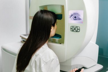 Göz perimetri testi, göz hastalıkları kliniğindeki kadının glokom belirtilerini gösteriyor. Kenar ya da çevresel görüş dahil olmak üzere tüm görüş alanlarını ölçmek için perimetri görsel alan testi