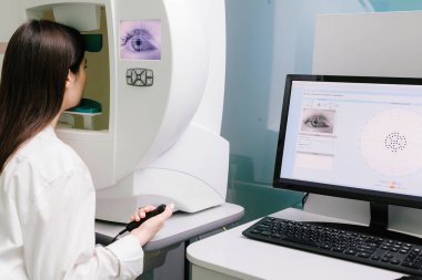 Yan ve çevresel görüş dahil olmak üzere tüm görüş alanlarını ölçmek için perimetri görsel alan testi. Göz perimetri testi, göz hastalıkları kliniğindeki kadının glokom belirtilerini gösteriyor.