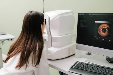 Optik tutarlılık tomografisi kullanan hastaların gözleri inceleniyor. Oftalmolog kız hastaların kornealarını tarıyor. Göz arkası görüntülerini oluşturmak için optik tutarlılık tomografisi OCT taraması