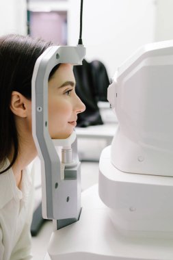 Göz arkası görüntülerini oluşturmak için optik eşkenar tomografi tomografisi. Optik tutarlılık tomografisi kullanan hastaların gözleri inceleniyor. Oftalmolog kız hastaların kornealarını tarıyor.
