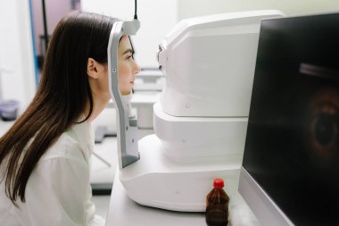 Optik tutarlılık tomografisi kullanan hastaların gözleri inceleniyor. Oftalmolog kız hastaların kornealarını tarıyor. Göz arkası görüntülerini oluşturmak için optik tutarlılık tomografisi OCT taraması