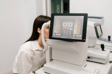 Gelişmiş optik eşkenar tomografi cihazları kullanılarak OKT göz muayenesine tabi tutuluyor. Yüksek çözünürlüklü ekranda göz hastalıklarının erken teşhisine yardımcı olan retina taramaları görülüyor.