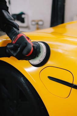 Spor arabayı cilalamak, çizikleri silmek için aşındırıcı macunla cilalamak. Tamir atölyesinde araba cilası cilalayan araba tamircisinin elleri.