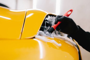 Spor araba farlarını temizleme işlemi sırasında sabun köpüğü ve fırçayla yıkanır. Araba farları köpük ve yumuşak fırçayla temizleniyor