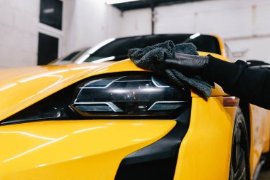 Spor araba temizleme işlemi. Farı mikrofiber bezle parlatmak. İşçi araba farı cilası için mum sıvısı kullanır