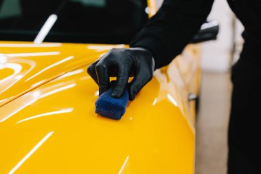 Detaylı servis çalışanı spor arabaya seramik koruma sıvısı uygular. Sarı spor araba için koruyucu nano katman oluşturmak için seramik sıvıyı karıştırmak
