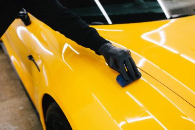 Detaylı servis çalışanı spor arabaya seramik koruma sıvısı uygular. Sarı spor araba için koruyucu nano katman oluşturmak için seramik sıvıyı karıştırmak