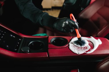 Araba yıkatma işlemi araba yıkamada sabun köpüğüyle temizleniyor. Adam arabanın kırmızı derisine köpük sürüp temizler.