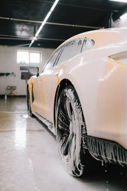 Araba yıkama sırasında oto servisinde sabun köpüğüyle yıkanan spor araba. Titiz araba temizliği sırasında sabunla yıkama işlemi