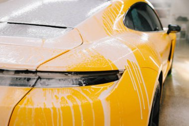 Araba yıkama sırasında oto servisinde sabun köpüğüyle yıkanan spor araba. Titiz araba temizliği sırasında sabunla yıkama işlemi