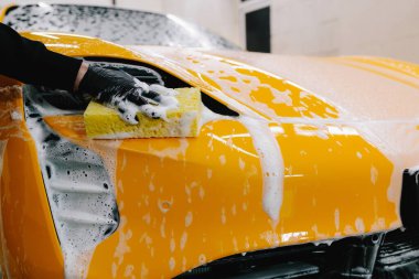 Araba servisinde temizlik için köpüklü süngerle araba yıkamak. Detaylandırmak için ayarlanmış bir araba hazırlanıyor