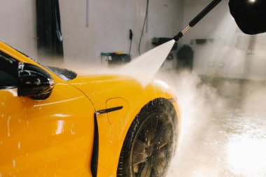 Araba yıkamak için yüksek basınçlı su tabancası kullanmak. Araba yıkamada su tabancasından araba yıkama işlemi.