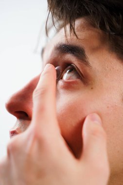 Adam miyop tedavisi için gözüne kontak lens takıyor. Optik kontakt lenslerle göz sağlığının düzeltilmesi