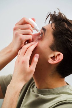 Adamın gözü tahriş sorunu yüzünden damlıyor. Evde göz damlası ile göz tedavisi uygulanıyor. Adam alerji tedavisi için göz damlası kullanıyor.