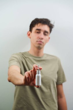 Sinüzit tedavisi ve beyaz arka planda eczane damlaları. Burun spreyi beyaz şişesi insanların elinde.