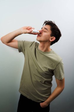 Hasta adam evde akan burundan kurtulmak için burun damlası enjekte ediyor. Adam tedavi için burun spreyi kullanıyor.