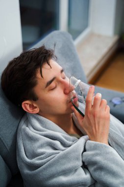 Hasta adam nebulizatörle solunum tedavisi görüyor. Evde öksürük tedavisi için nebulizör maskesiyle hava solumak