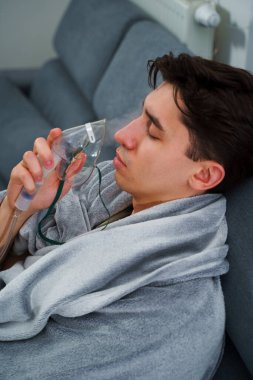 Hasta adam nebulizatörle solunum tedavisi görüyor. Evde öksürük tedavisi için nebulizör maskesiyle hava solumak