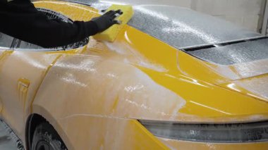 Araba servisinde temizlik için köpüklü süngerle araba yıkamak. Spor arabayı detaylı işleme hazırlarken 4k video