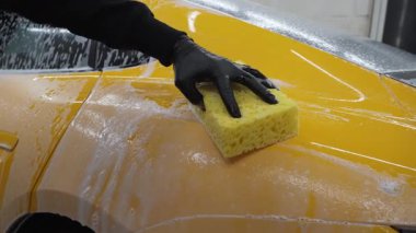 Araba servisinde temizlik için köpüklü süngerle araba yıkamak. Spor arabayı detaylı işleme hazırlarken 4k video