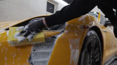 Spor arabayı detaylı işleme hazırlarken 4K video. Araba servisinde temizlik için köpüklü süngerle yıkama.