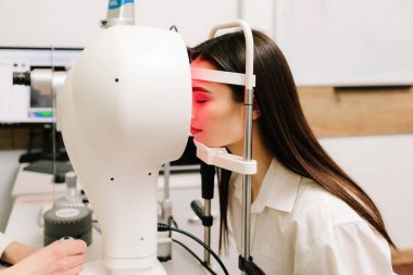 Korneanın şekli ve gücünün görsel tanımı için kornea topografisi göz görme testi. Kornea topografının kırmızı ışığı topoğrafya sınavında kadının üzerine parlıyor