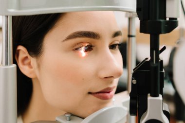 Göz farı ve kornea teşhisi, göz hekimliği kliniğinde. Kesik lambanın gözündeki ışık incelenmek için gözleri ve kızın korneası için.