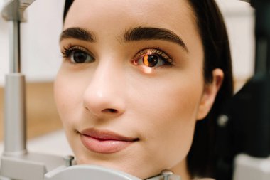 Kesik lambalı bir oftalmolog kadının gözlerini ve korneasını inceliyor. Göz doktoru, göz ve kornea teşhisi koymak için kesik lambadan gelen ışıkla hastanın gözünü aydınlatıyor.