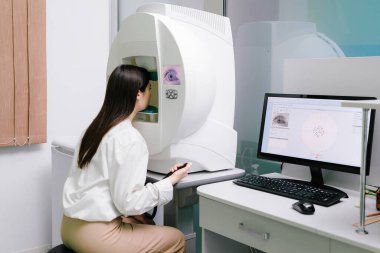 Göz perimetri testi, göz hastalıkları kliniğindeki kadının glokom belirtilerini gösteriyor. Kenar ya da çevresel görüş dahil olmak üzere tüm görüş alanlarını ölçmek için perimetri görsel alan testi