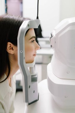 Optik tutarlılık tomografisi kullanan hastaların gözleri inceleniyor. Oftalmolog kız hastaların kornealarını tarıyor. Göz arkası görüntülerini oluşturmak için optik tutarlılık tomografisi OCT taraması