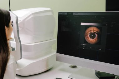 Göz arkası görüntülerini oluşturmak için optik eşkenar tomografi tomografisi. Optik tutarlılık tomografisi kullanan hastaların gözleri inceleniyor. Oftalmolog kız hastaların kornealarını tarıyor.